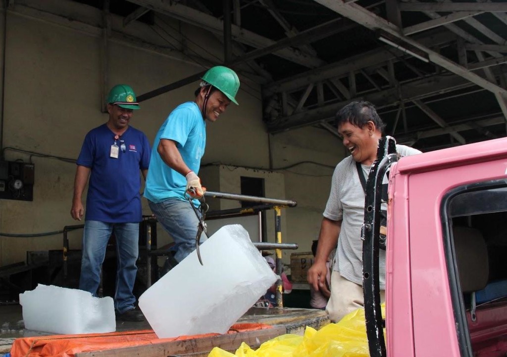 KEEPING IT COOL. Jerry Baisac (leftmost), an employee of Cotabato Ice Plant for 30 years now, supervises the loading of ice blocks onto a customer’s fish delivery truck. 
