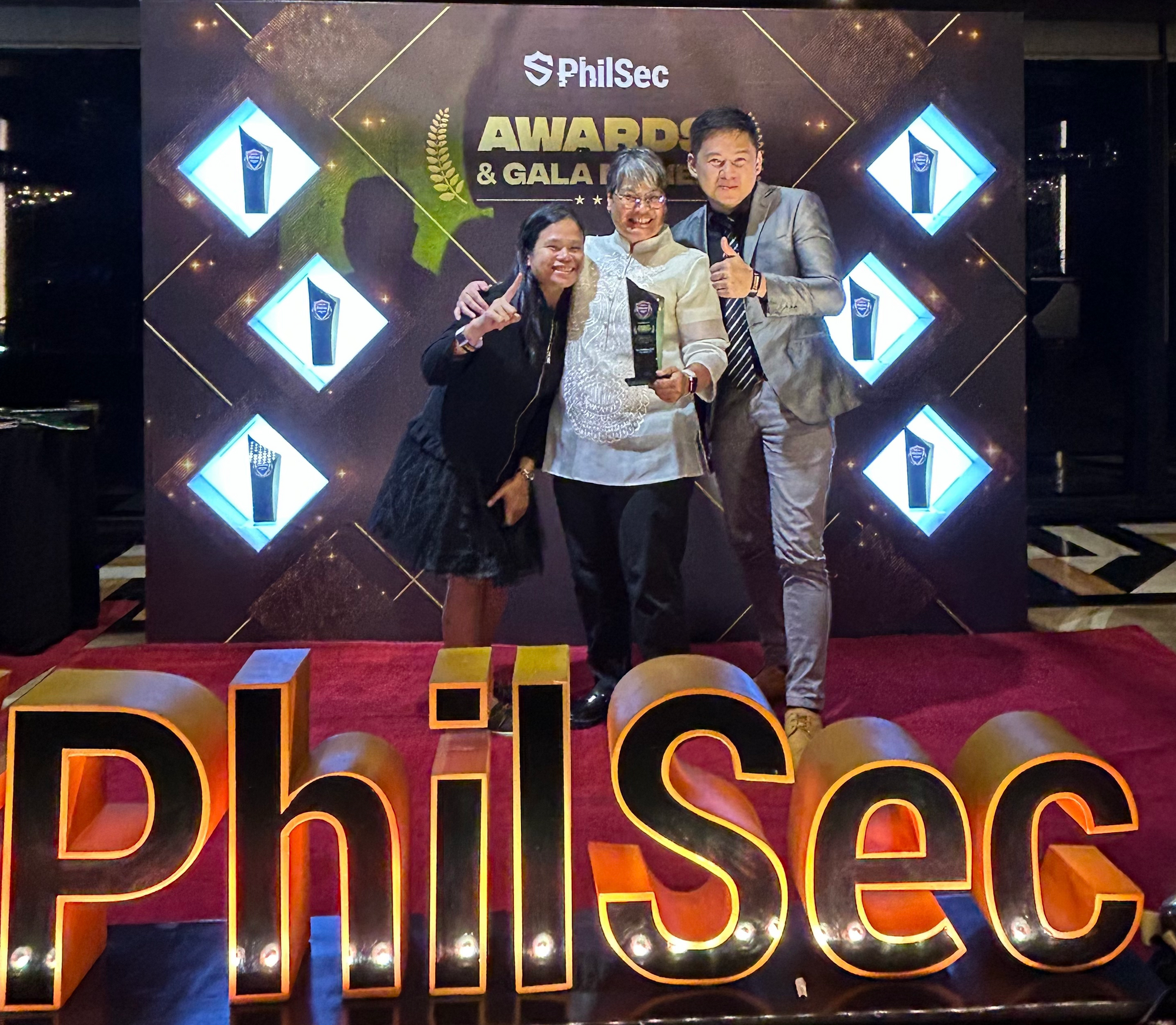 Charm accepts the award on behalf of her dedicated team, ensuring security services for the organization and society. Pictured with Charm are team members Ronadell Hongo (left) and John Michael Nguyen (right).